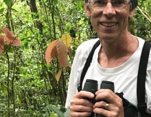 Portrait of Philip Stoddard ’79 holding binoculars. 